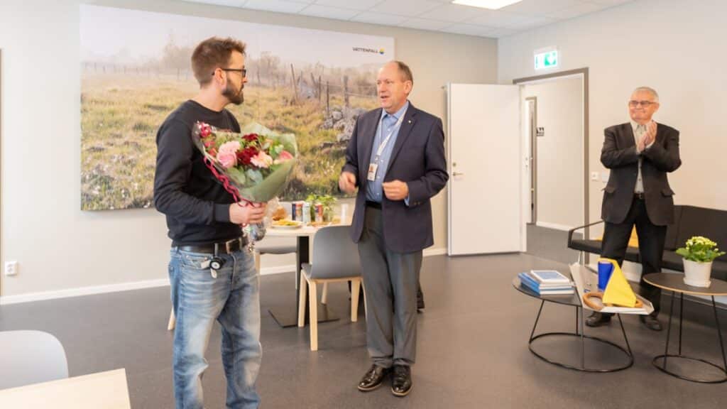 En man överräcker en blombukett till en annan man.