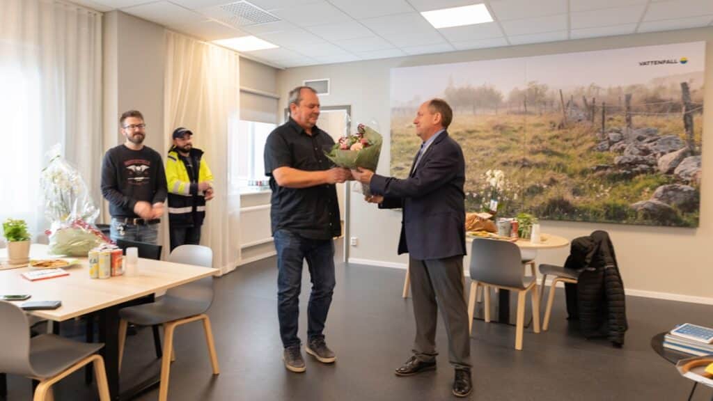 En man överräcker en blombukett till en annan man.