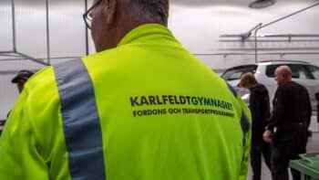 En person står med ryggen mot kameran med texten "Karlfeldtgymnasiet Fordons- och transportprogrammet".